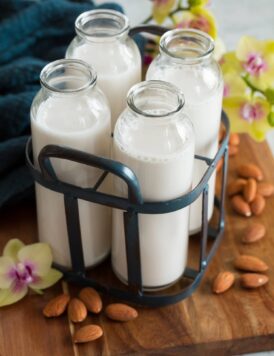 Four servings of almond milk in a vintage milk carrier.