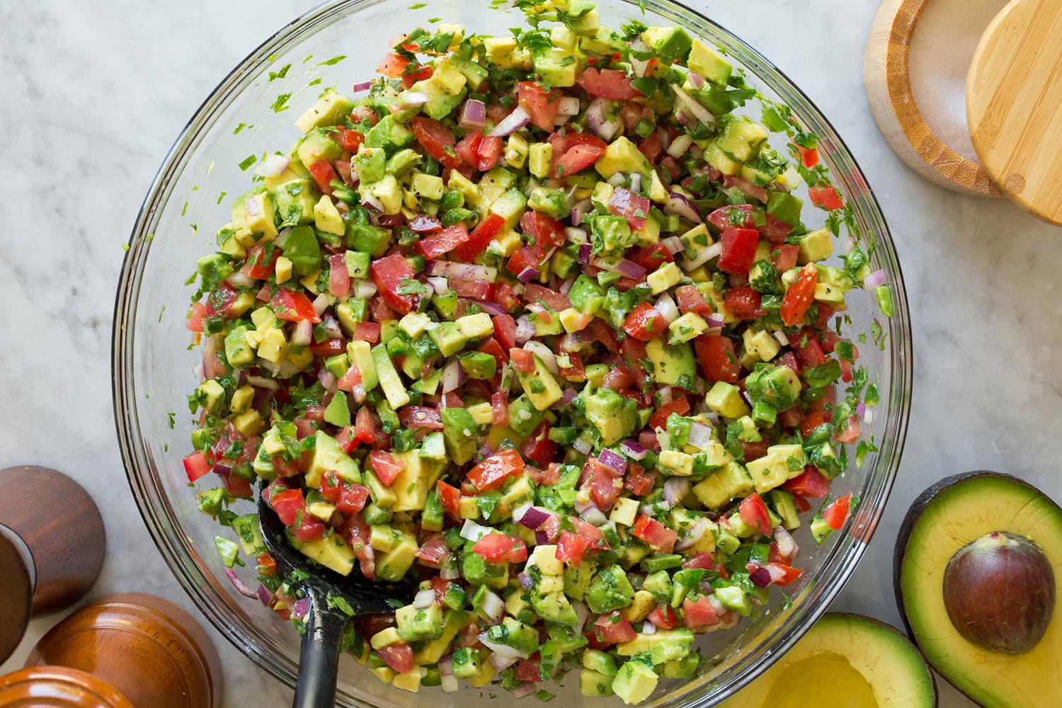 Avocado salsa in a glass mixing bowl shown after tossing ingredients together.