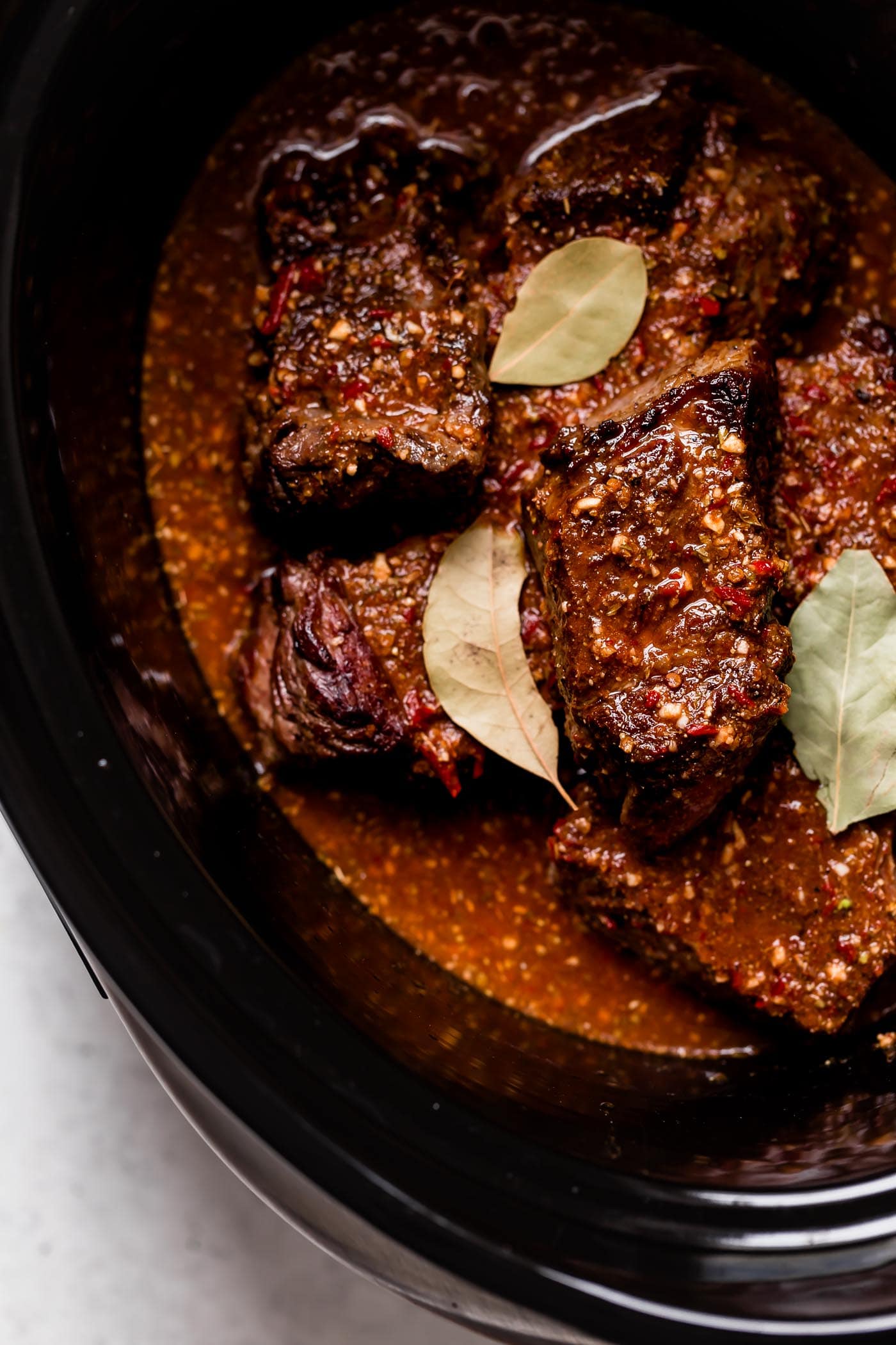 Barbacoa beef in slow cooker shown in chunks after cooking.