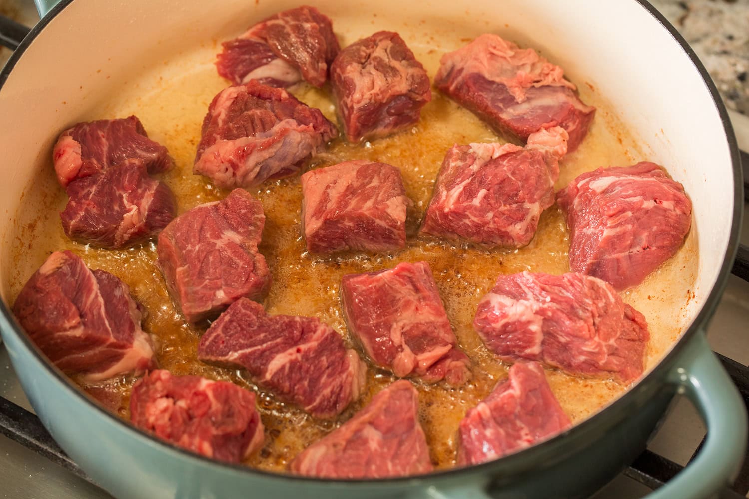 Beef chuck chunks shown before searing in a pot.