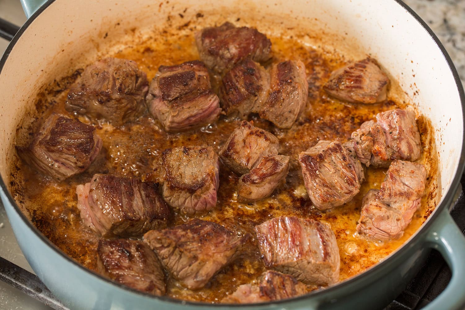 Beef chuck chunks shown after searing and browned in a pot.