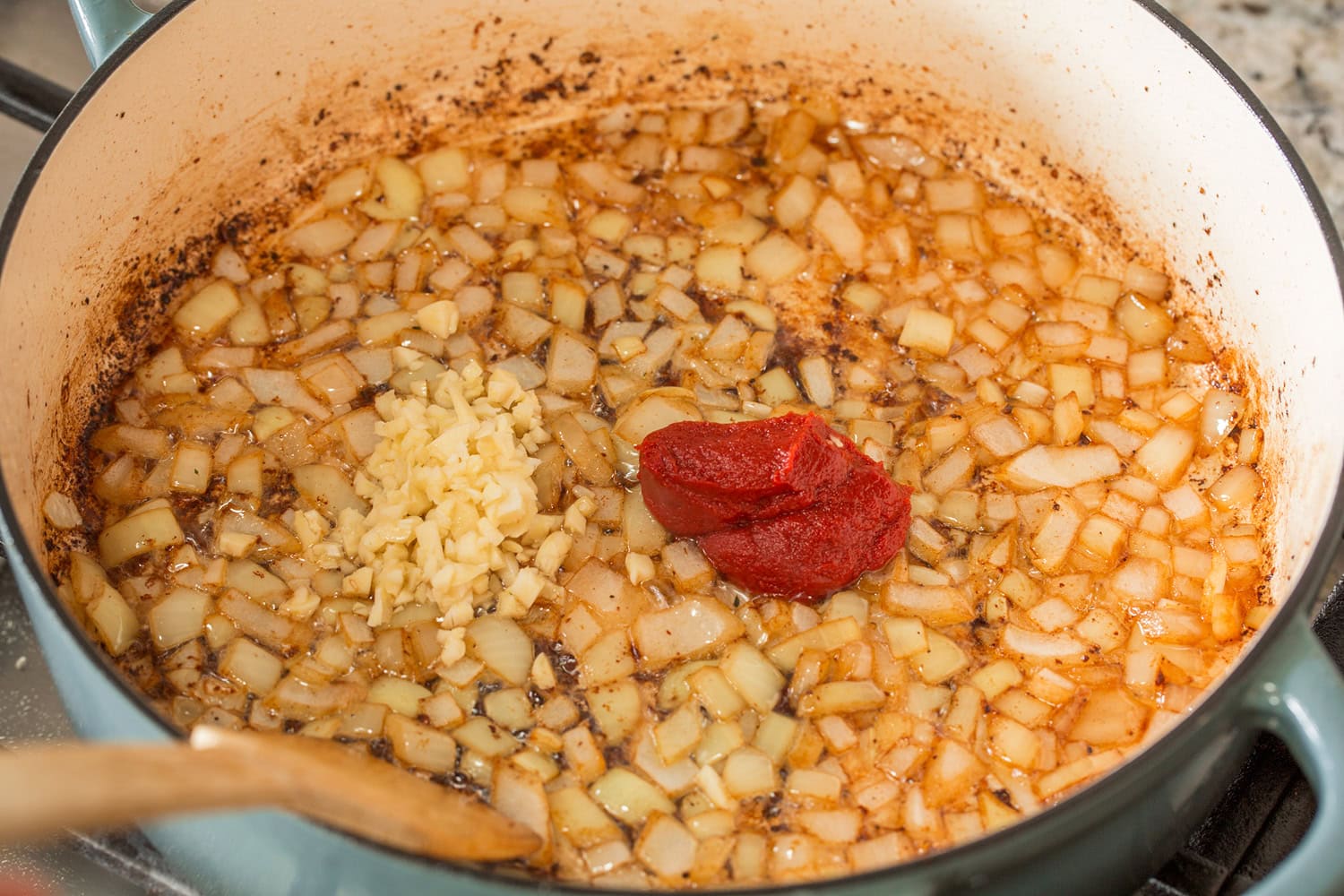 Onion added to pot with tomato paste and garlic.