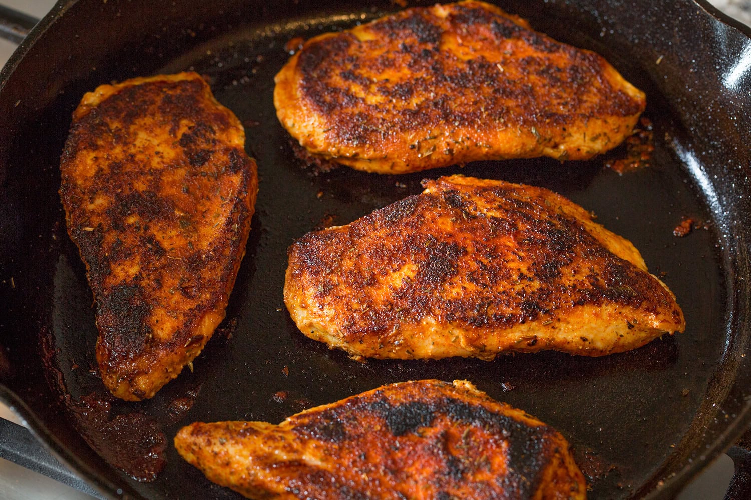 Blackened chicken in cast iron skillet with both sides cooked.