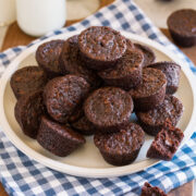 Homemade brownie bites stacked together on a plate over a blue checkered napkin.