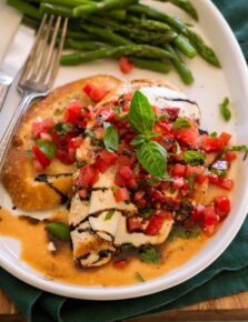 Bruschetta Chicken served with balsamic glaze and a side of toasted baguette and asparagus.