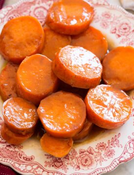 Close up image of candied yams on a red and white decorative side plate.