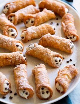 Cannoli with ricotta and chocolate chip filling on a white serving platter.