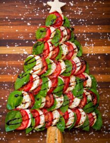 Caprese Christmas tree with fresh mozzarella, tomato slices, fresh basil leaves, balsamic glaze and sea salt flakes.