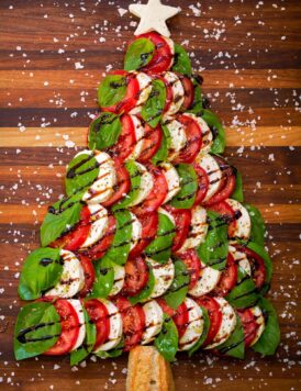 Caprese Christmas tree with fresh mozzarella, tomato slices, fresh basil leaves, balsamic glaze and sea salt flakes.