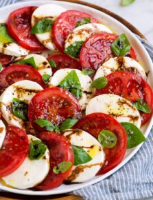 Caprese salad layered in a pretty design shown on a white platter.