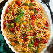 Cherry tomato pasta on a white oval scalloped serving platter.