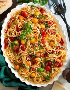 Cherry tomato pasta on a white oval scalloped serving platter.