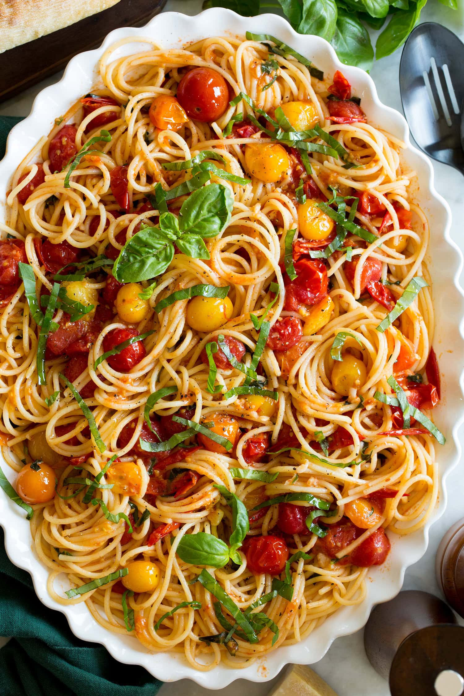 Close up photo of spaghetti with cherry tomato sauce and basil.