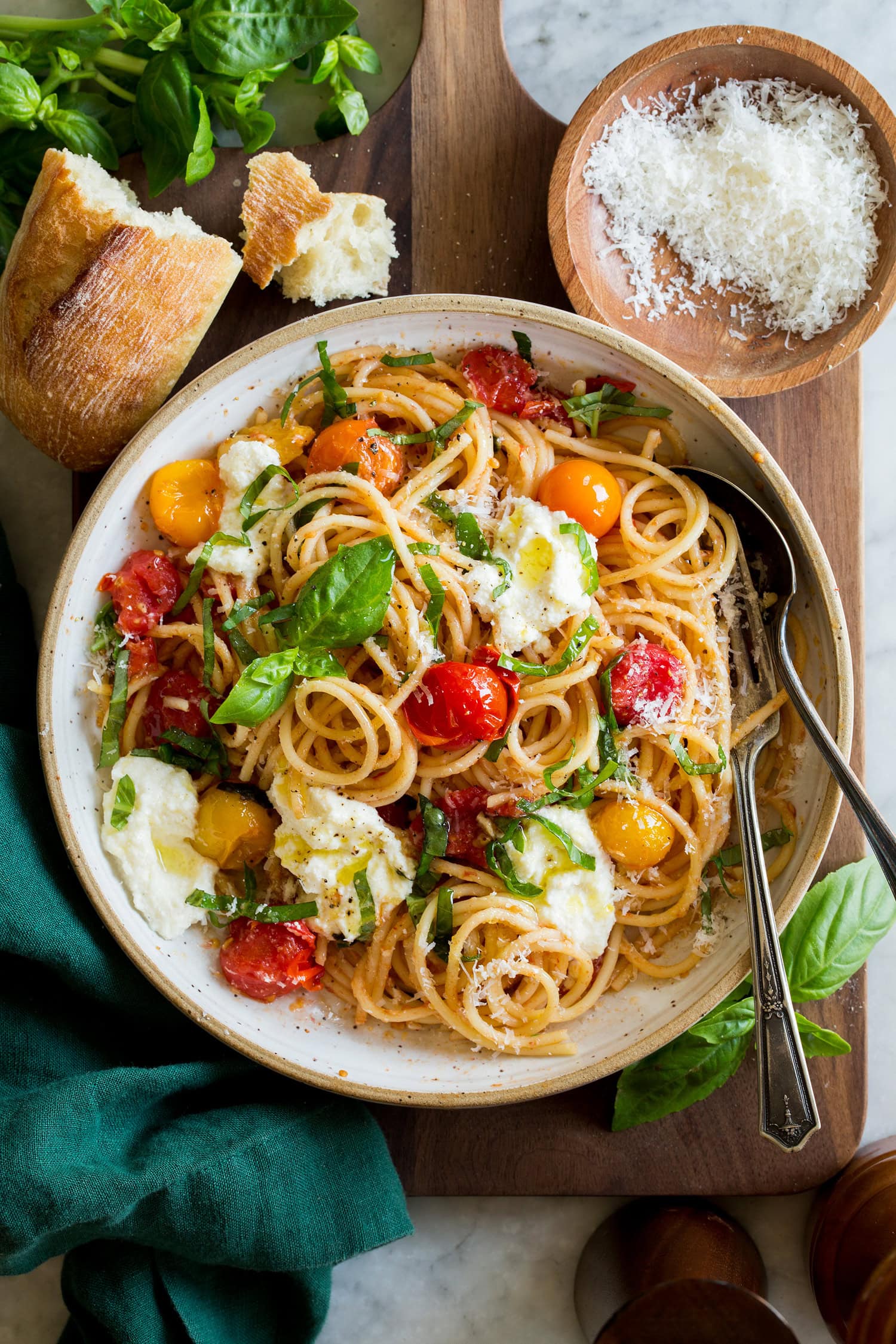 Cherry tomato pasta serving shown in a ceramic bowl with dollops of ricotta and grated parmesan on top.