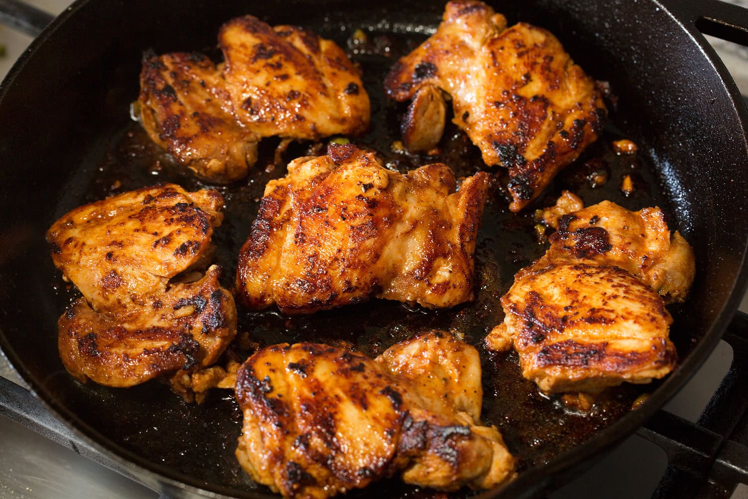 Chicken thighs seared in a cast iron skillet.