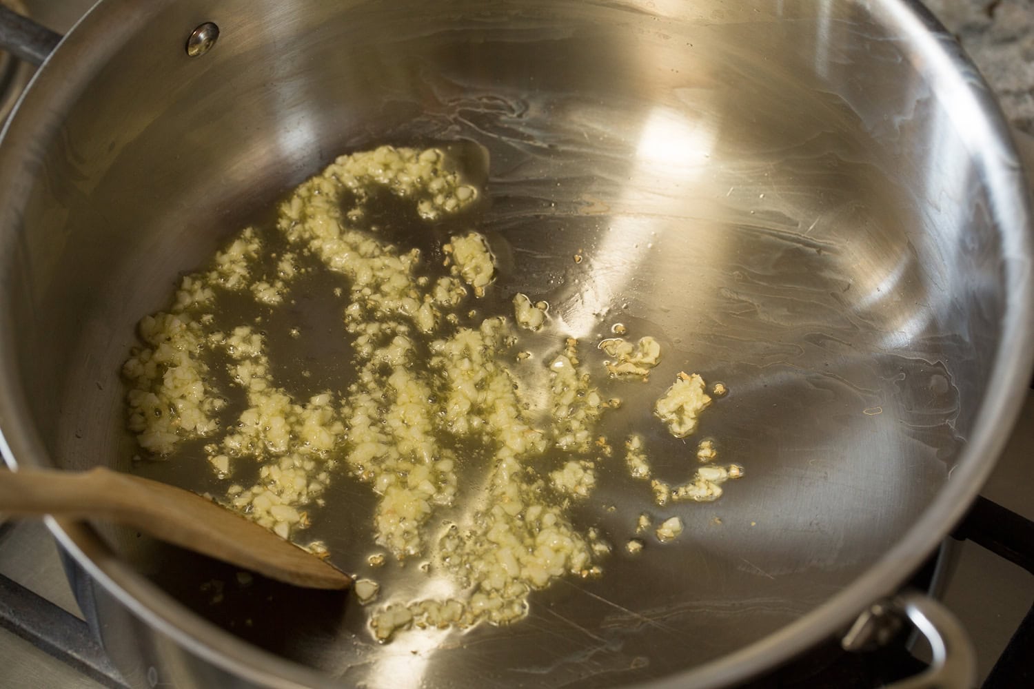 Garlic sauteing in oil in a pot.