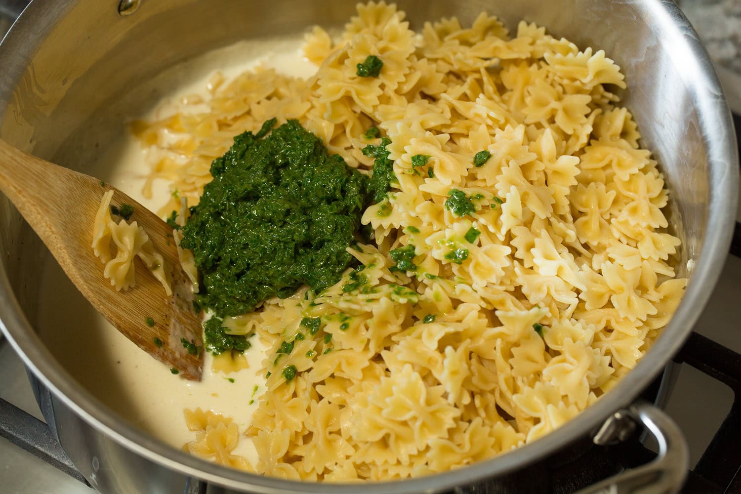 Pasta and basil mixture added to cream mixture in pot.