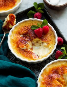 Creme brulee shown on a vintage baking sheet. Sugar shell is broken to show interior custard cream filling.