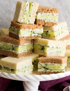 Close up photo of stack of cucumber sandwiches on a cake stand.