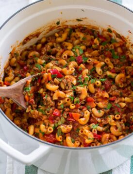 Goulash with macaroni, ground beef, and vegetables in a white pot.