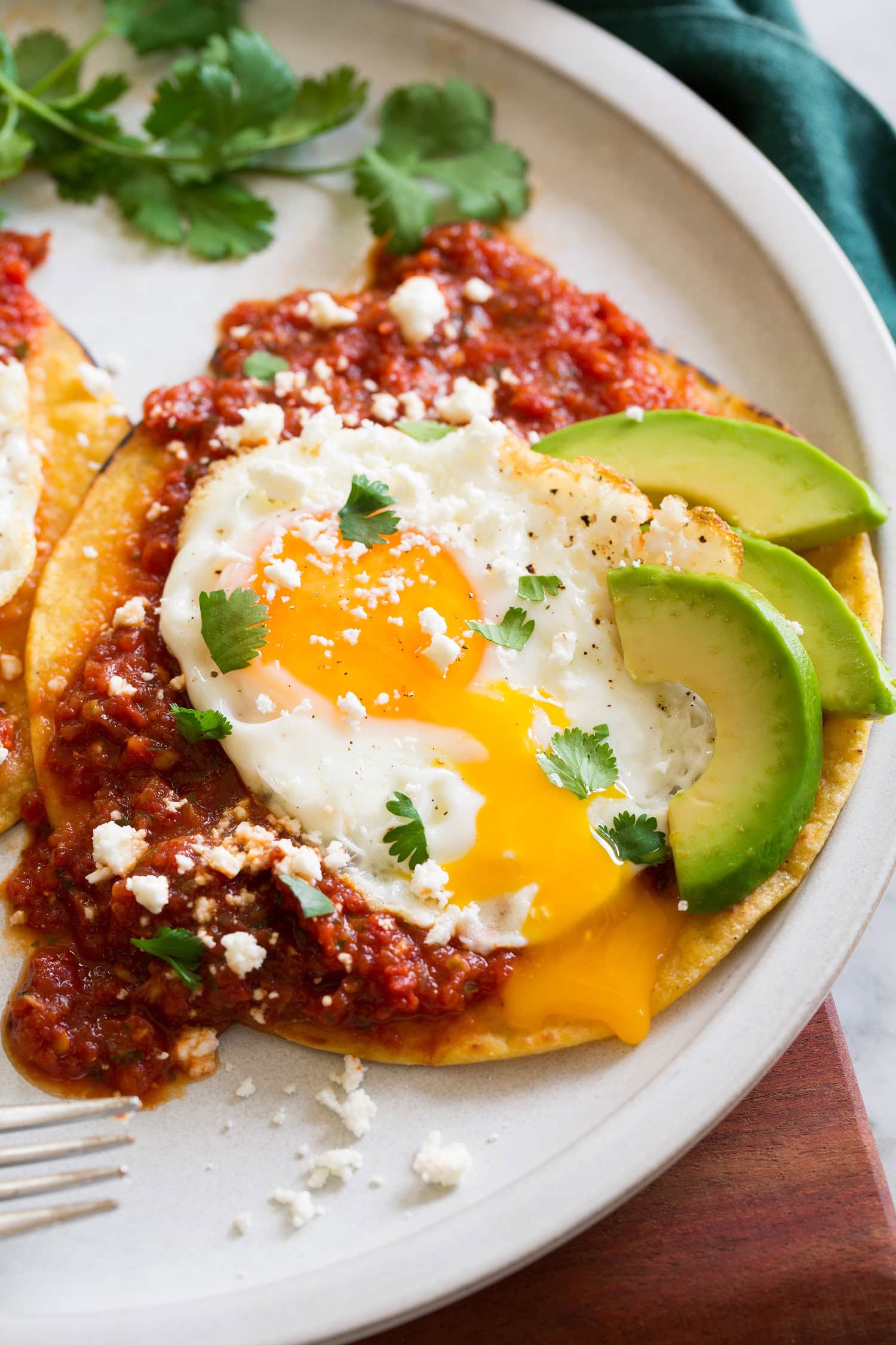 Close up photo of huevos rancheros with egg yolk running down side.