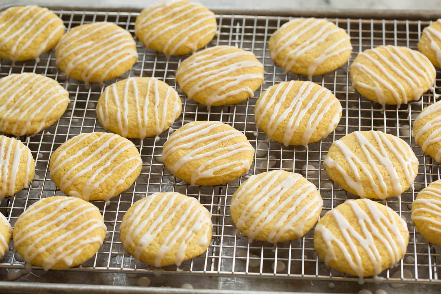 Lemon cookies on a wire rack after icing is drizzled over.