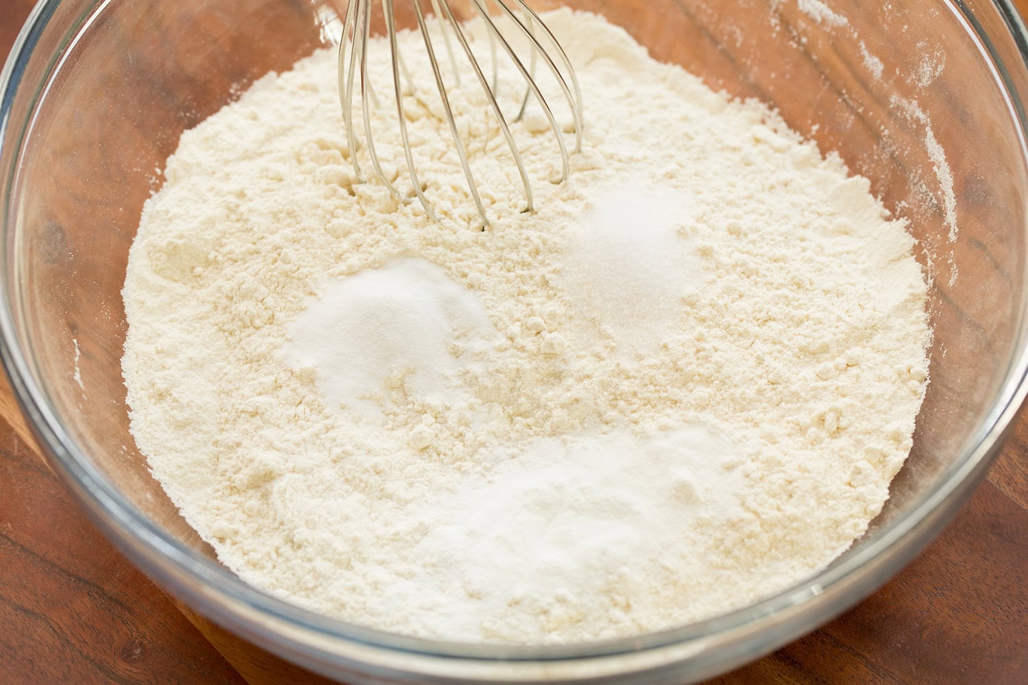 Flour mixture with baking powder, baking soda and salt in glass mixing bowl with whisk. First step of making lemon cookies.