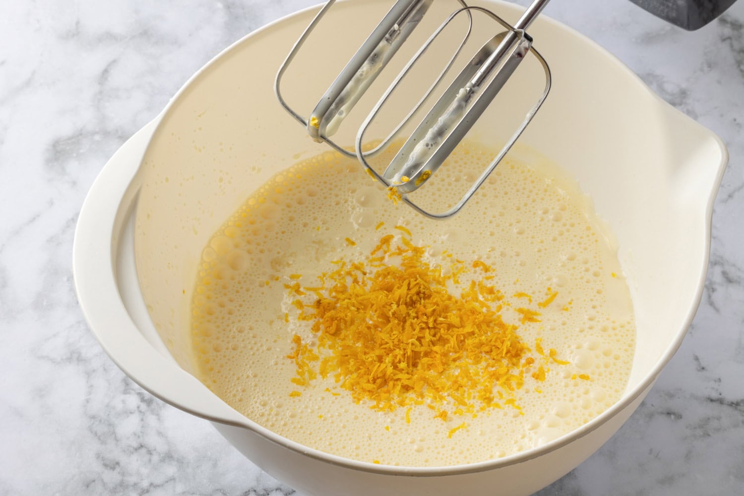 Lemon zest added to mixture in mixing bowl.