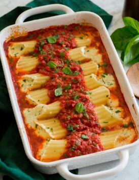 Homemade manicotti stuffed with cheese in a baking dish with marinara sauce.