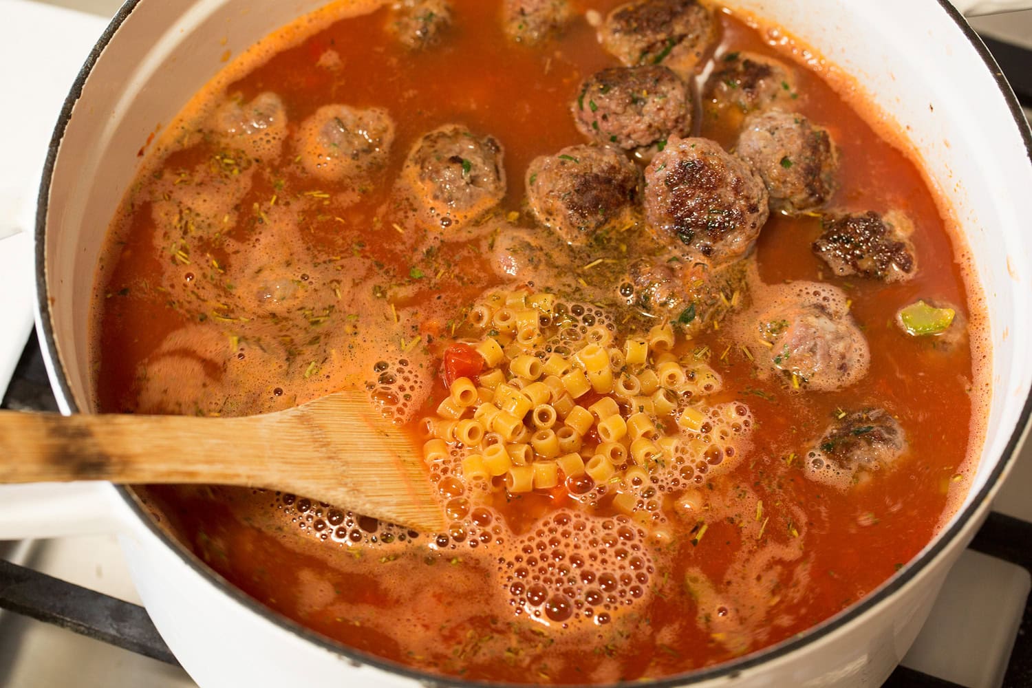 Tomatoes, broth, seasoning, meatballs and pasta added to soup.