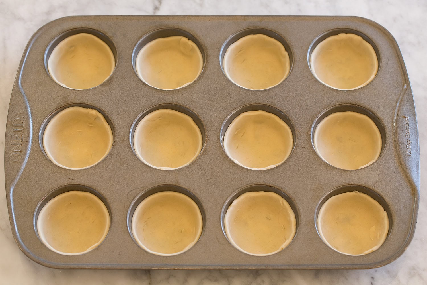 Pie crusts pressed into muffin pan.