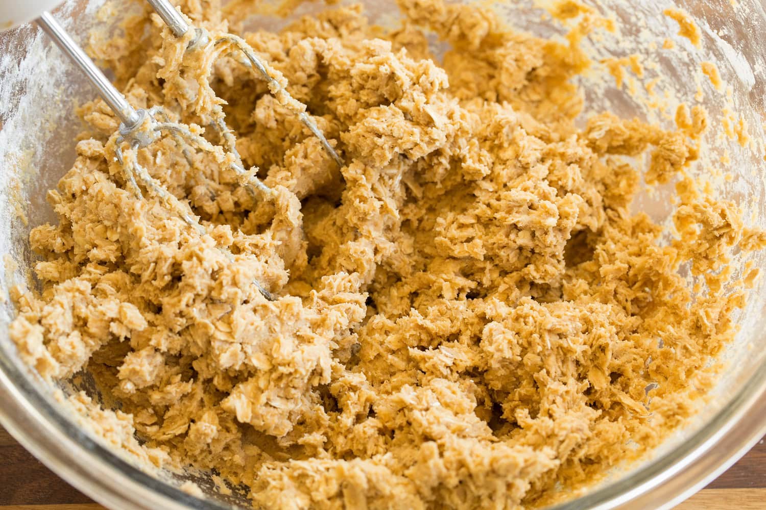 Blended oatmeal cookie dough in glass mixing bowl.