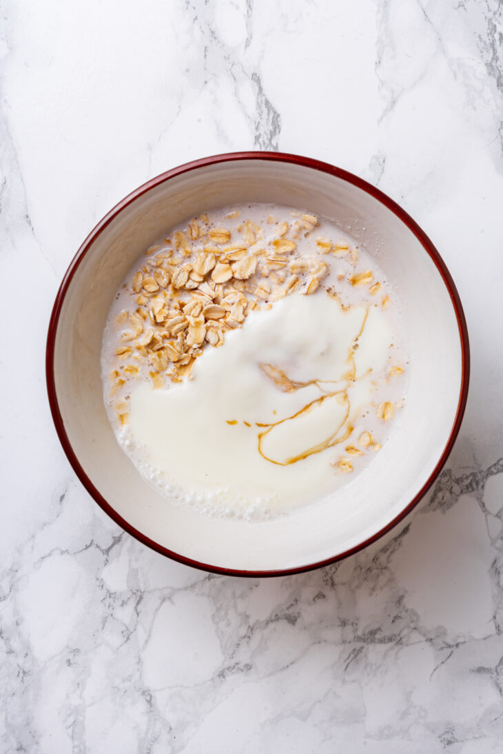 Oats, almond milk, and Greek yogurt combined in a bowl.