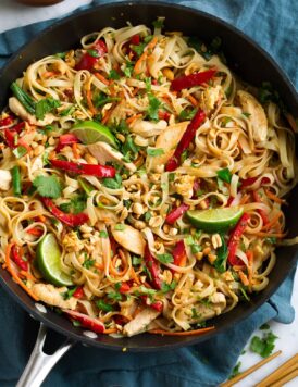 Pad Thai in a black wok with chicken and fresh vegetables.