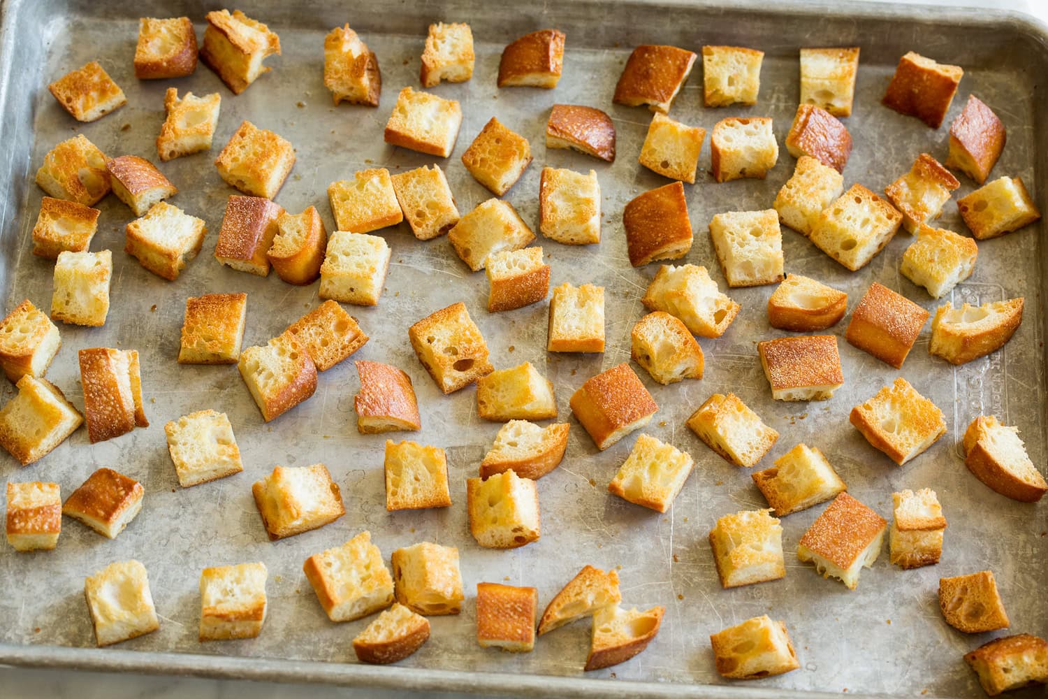 Toasted bread cubes on a baking sheet.