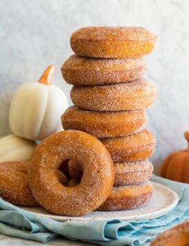 Stack of homemade baked pumpkin donuts covered in cinnamon sugar.