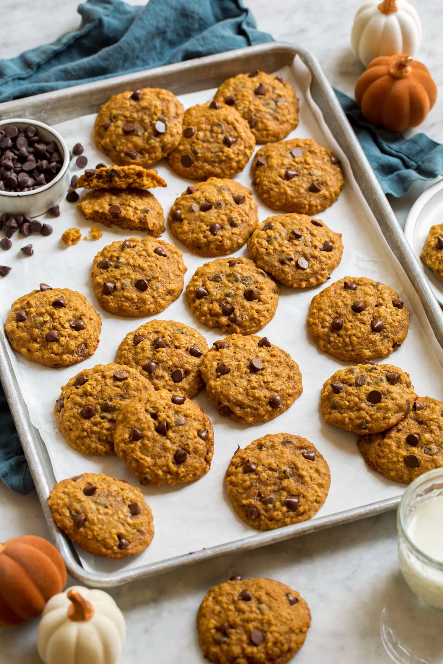 Pumpkin oatmeal chocolate chip cookies spread on parchment lined baking sheet.