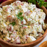 Red Potato Salad in a wooden bowl shown garnished with fresh parsley and dill.