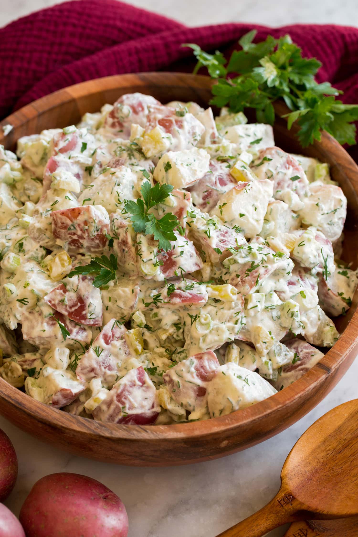 Red Potato Salad in a wooden bowl shown garnished with fresh parsley and dill.