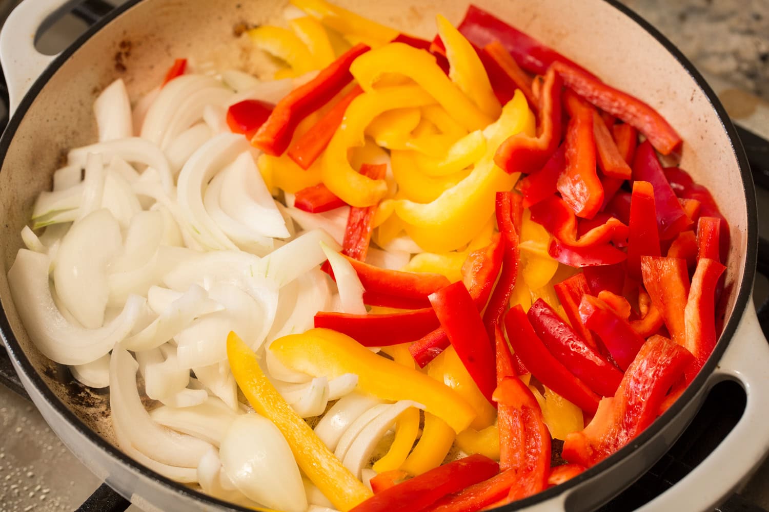 Adding raw peppers and onions to pan.