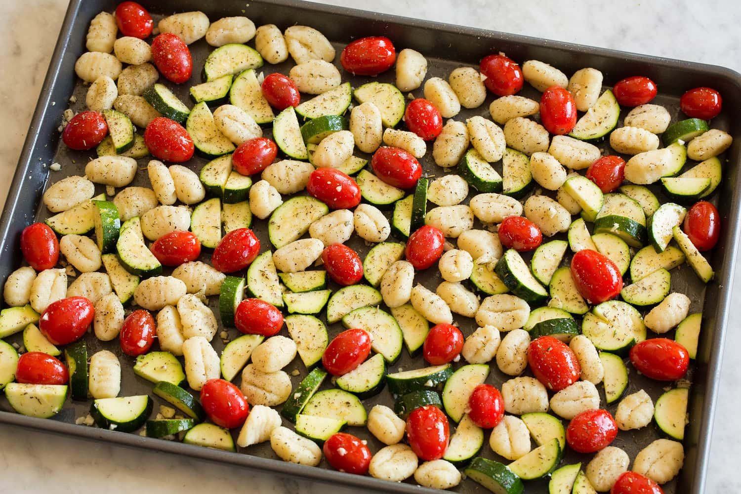 Tossed gnocchi mixture on baking sheet.