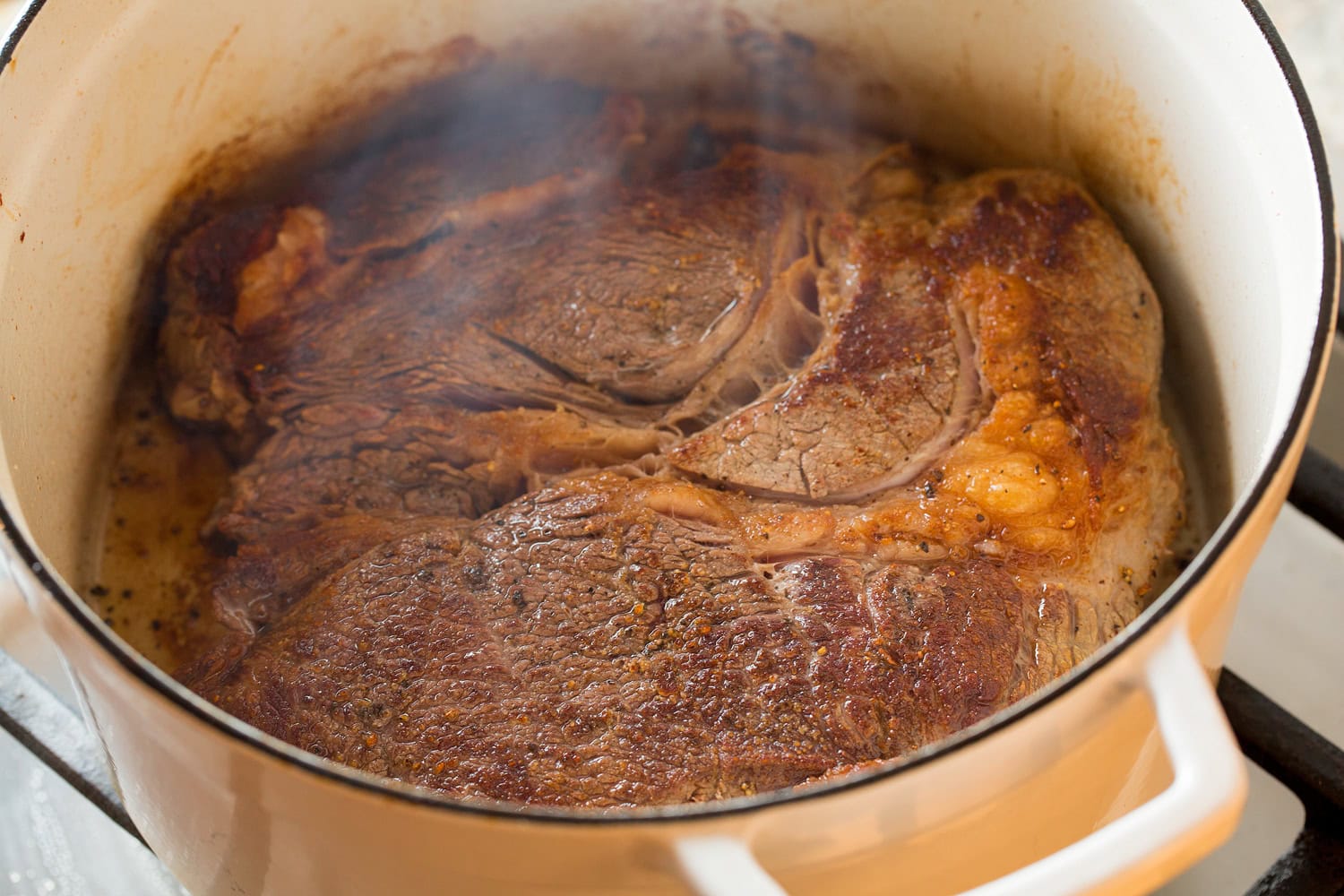 Seared chuck roast in a large pot.