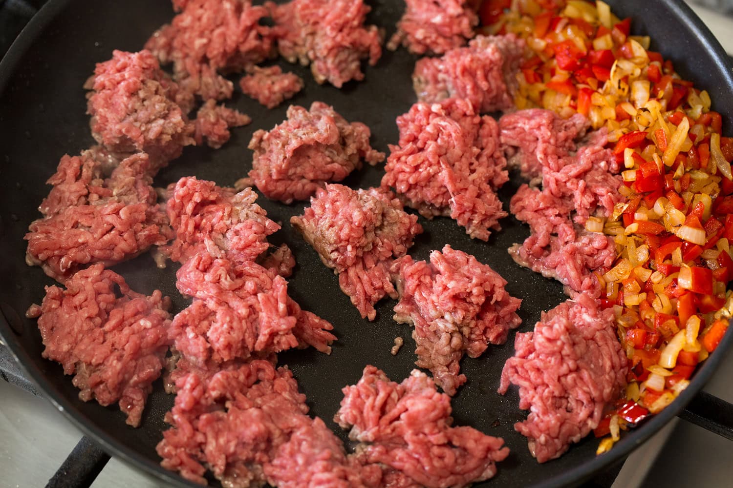 Ground beef chunks added to skillet with sauteed vegetables.