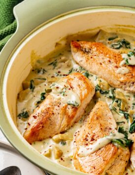 Creamy spinach artichoke chicken in a large skillet.