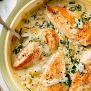 Overhead view of creamy spinach artichoke chicken in a large skillet.