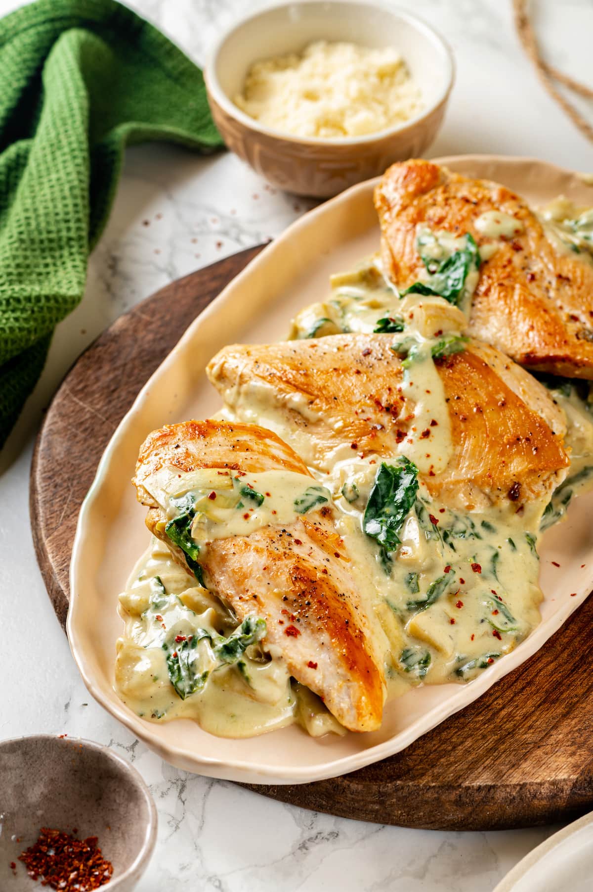 Creamy spinach artichoke chicken served on an oval platter.