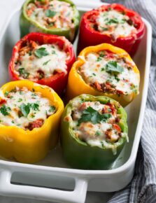 Multi-color stuffed peppers in a white baking dish.