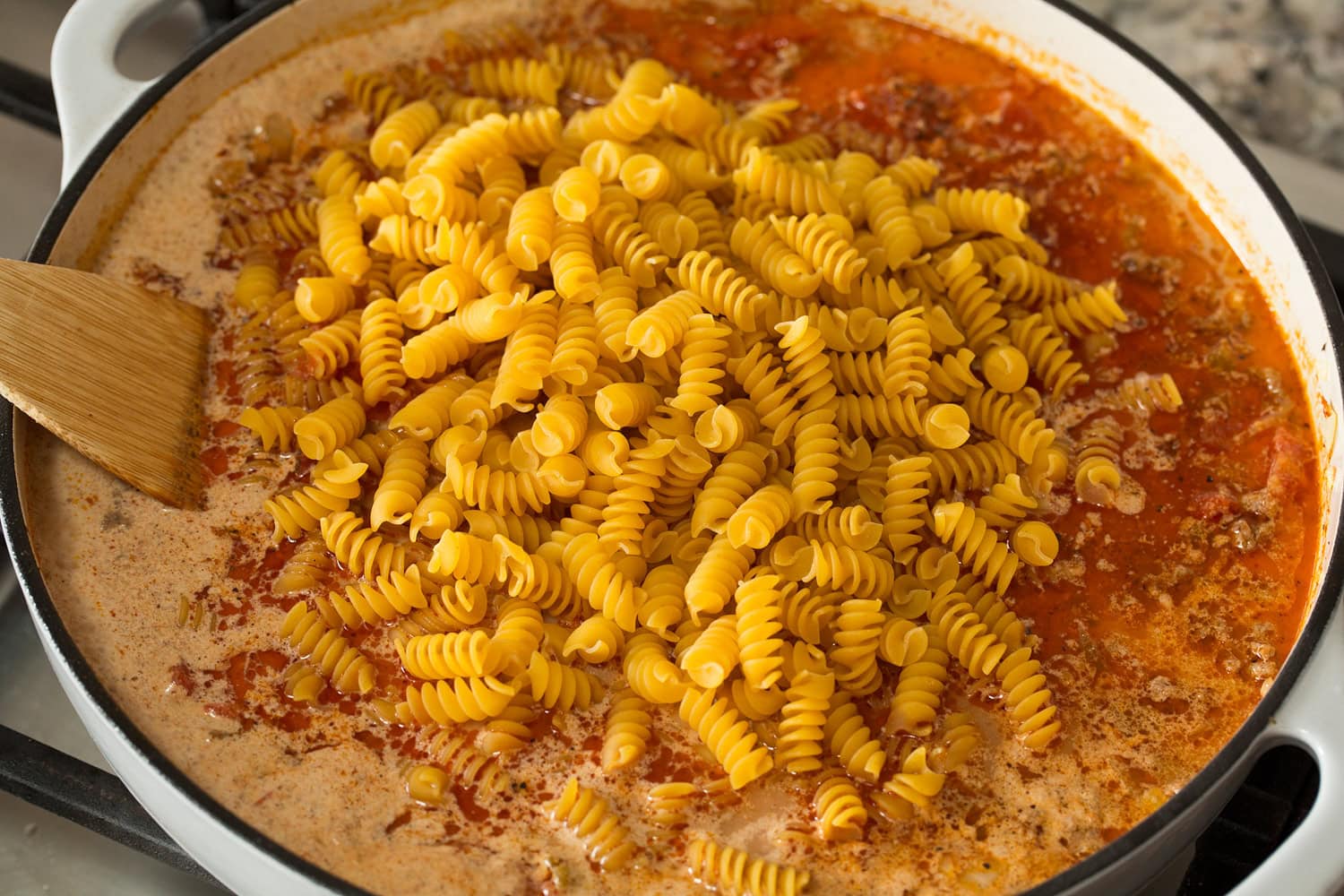 Pasta added to broth, beef mixture in pan.