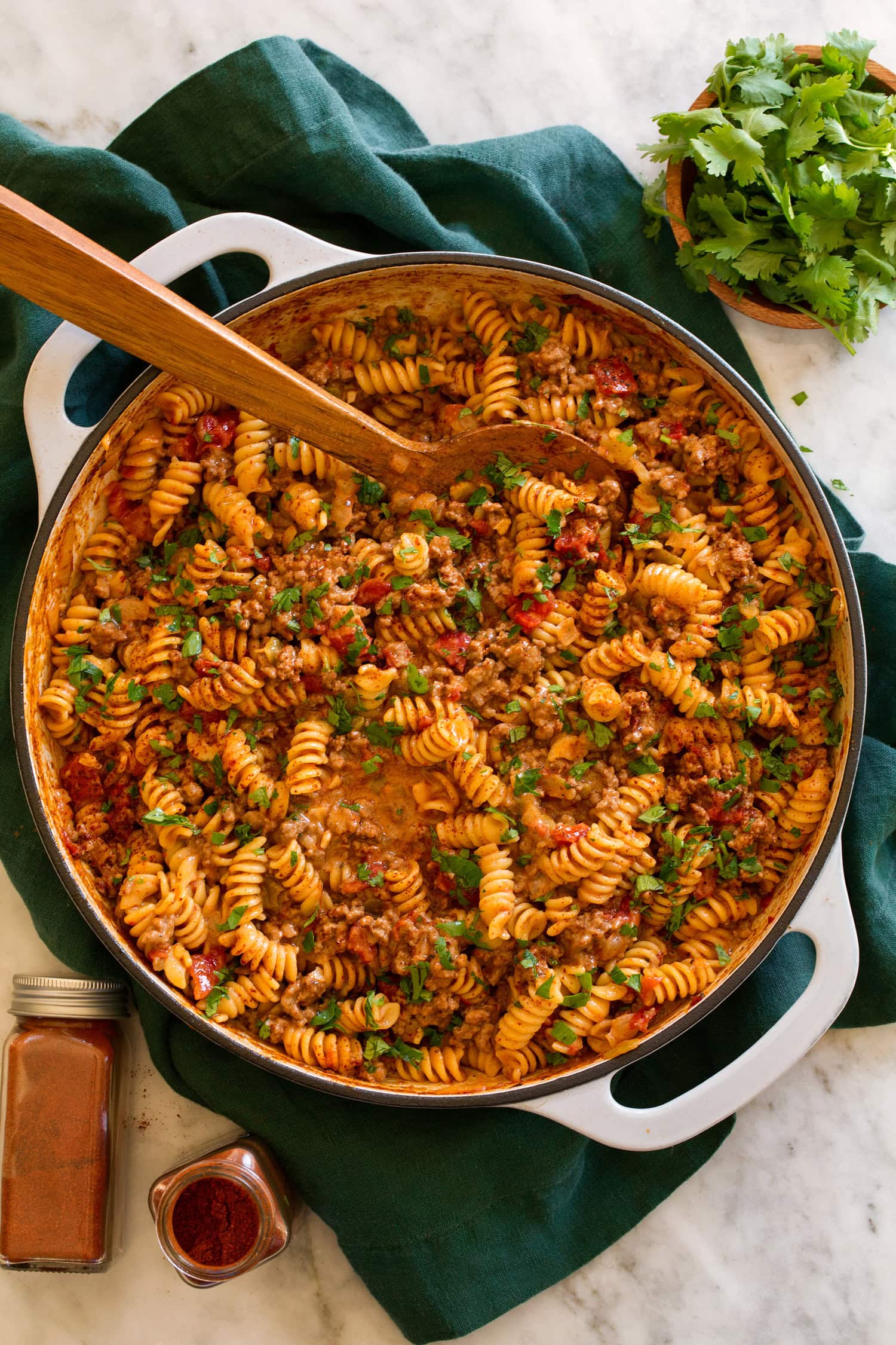 Taco pasta in a grey skillet over a green cloth on a marble surface.