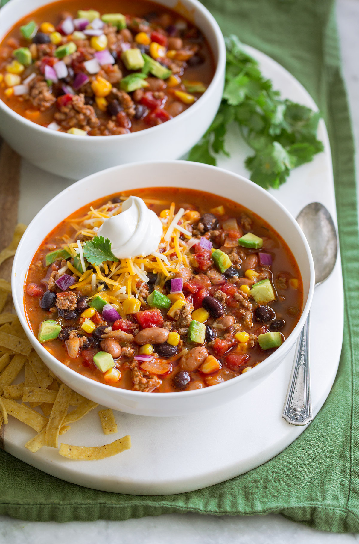 Two servings of taco soup in white bowls over a white platter.